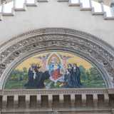 Al centro della facciata tre ampi archivolti dentati, vegetali e con sculture di angioletti racchiudono un lunettone a mosaico raffigurante Nostra signora del sacro cuore tra angeli e santi benedettini oranti